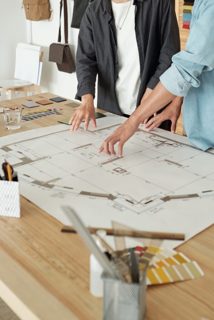 Young confident engineer showing his colleague sketch of construction